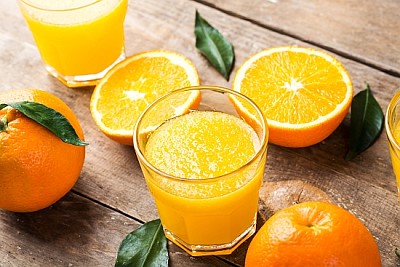 Suco de laranja espremido em um copo e laranjas frescas