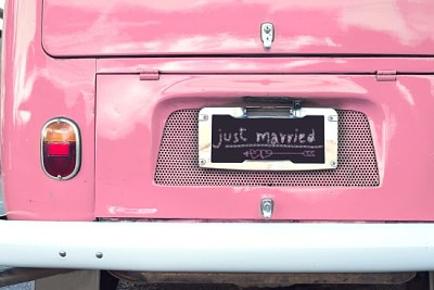 Recién casados firmar en furgoneta vintage clásica rosa