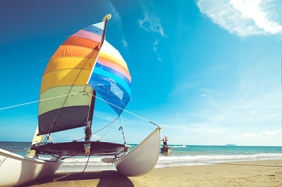 פאזל של סירת מפרש צבעונית על חוף טרופי בקיץ.