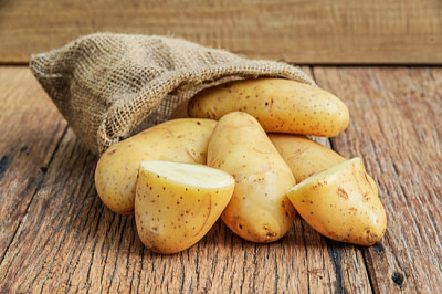 Pommes de terre biologiques crues dans le sac sur des planches de bois ba