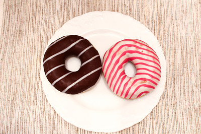 Pink and brown stripped donuts on plate on grey fa