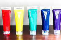 Standing colorful tubes with paint on wooden table